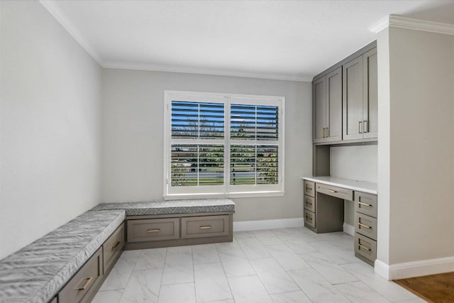 office space featuring crown molding, baseboards, built in desk, and marble finish floor