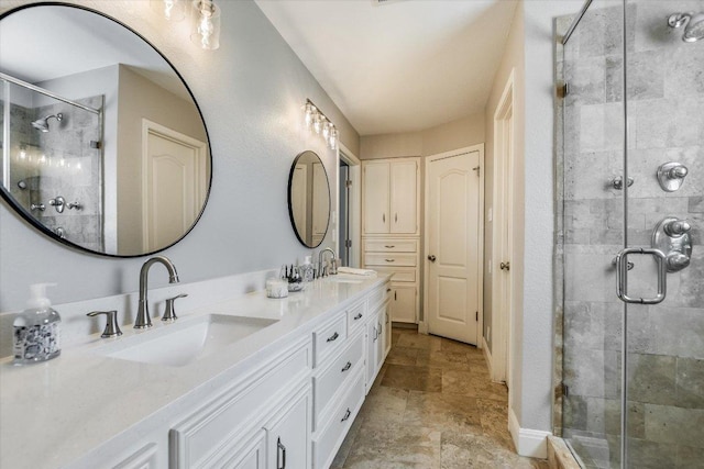 full bath with a sink, double vanity, a shower stall, and stone finish floor