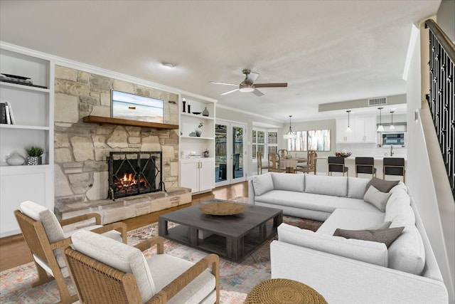 11402 Pencewood Dr, Austin, TX 78750 - living room featuring a ceiling fan, a fireplace, ornamental molding, wood finished floors, and built in shelves
