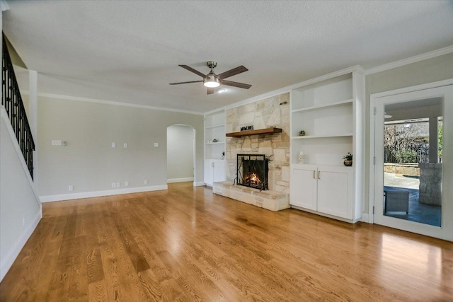 11402 Pencewood Dr, Austin, TX 78750 - unfurnished living room featuring ceiling fan, a fireplace, built in features, crown molding, and arched walkways