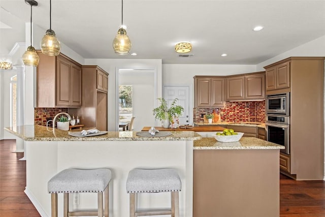 kitchen featuring light stone countertops, appliances with stainless steel finishes, a peninsula, and dark wood finished floors