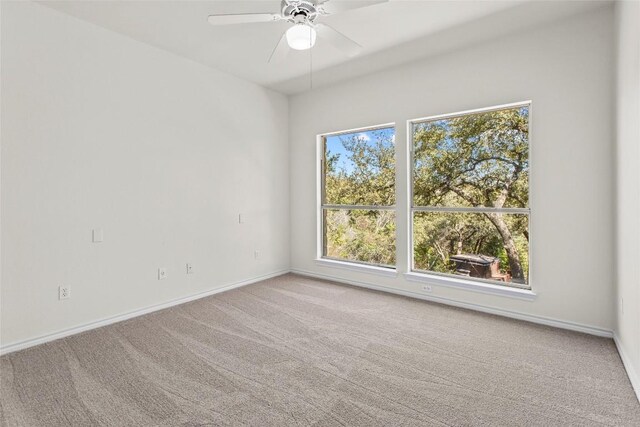 carpeted spare room with baseboards and ceiling fan