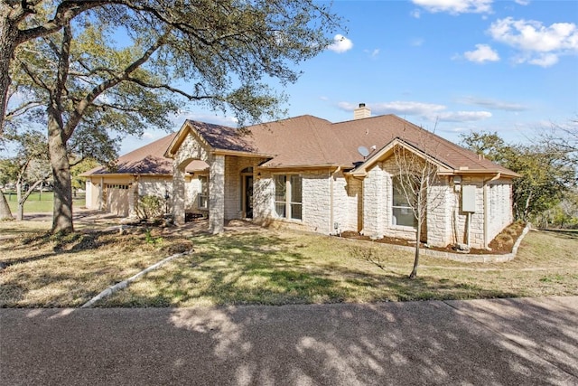 view of front of property with stone siding, a front lawn, a chimney, and a garage