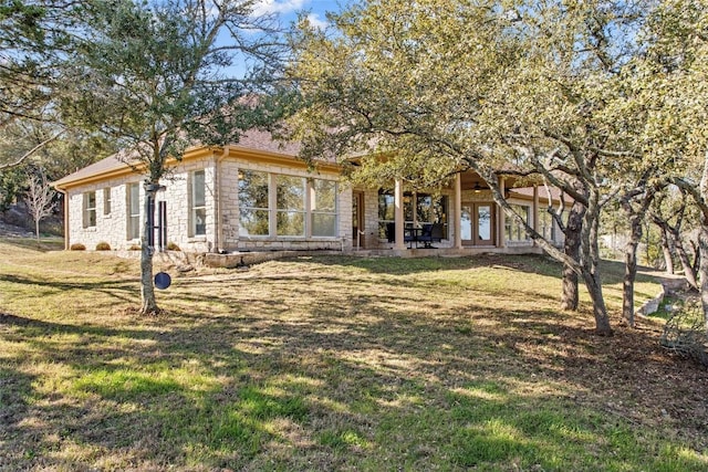 view of front of house featuring french doors, stone siding, and a front yard