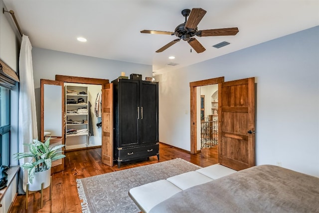 bedroom with a walk in closet, recessed lighting, wood finished floors, and visible vents