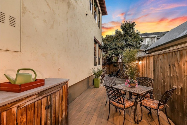 deck at dusk featuring fence