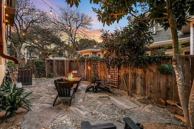 patio terrace at dusk featuring cooling unit, a fire pit, and fence