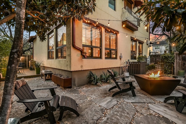 view of property exterior with a patio area, an outdoor fire pit, a deck, and fence