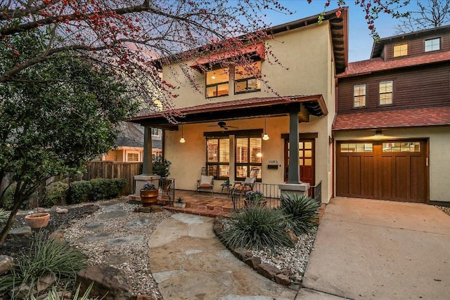 rear view of property featuring a porch, fence, driveway, and stucco siding