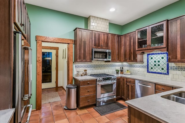 kitchen featuring decorative backsplash, light tile patterned floors, glass insert cabinets, and stainless steel appliances