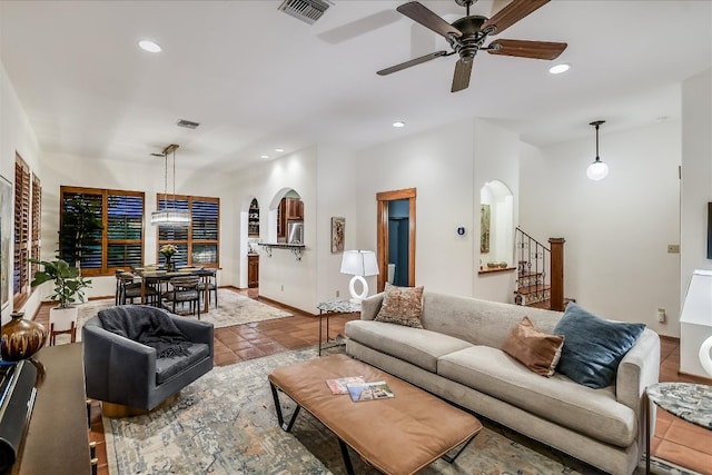 living area with stairway, recessed lighting, visible vents, and arched walkways