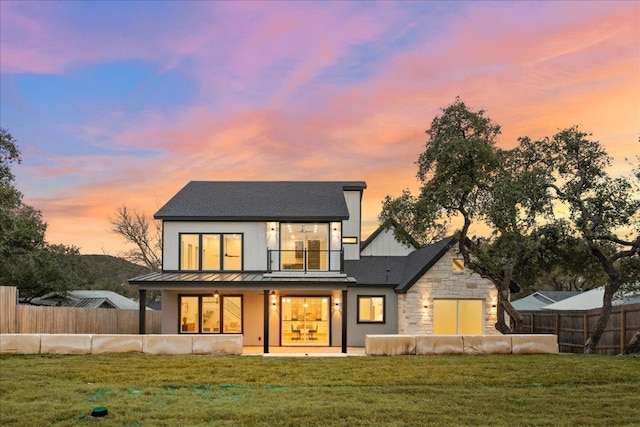 rear view of property with a fenced backyard, a lawn, and a balcony