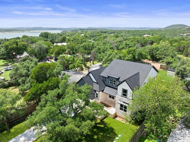 birds eye view of property with a wooded view and a water view