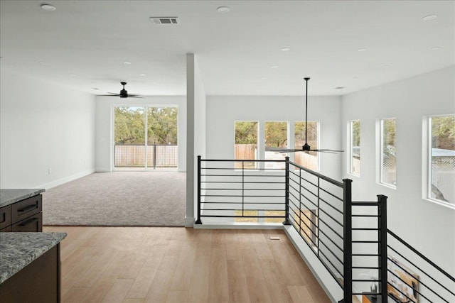 corridor with baseboards, visible vents, an upstairs landing, light colored carpet, and light wood-type flooring