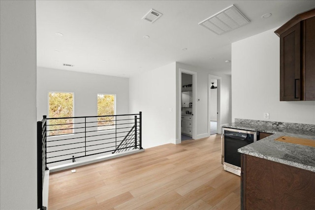 kitchen featuring visible vents, light wood-style flooring, stone countertops, dark brown cabinets, and dishwasher