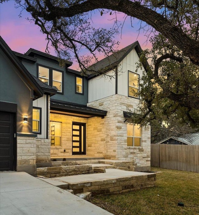 view of front of house with stone siding, stucco siding, and fence