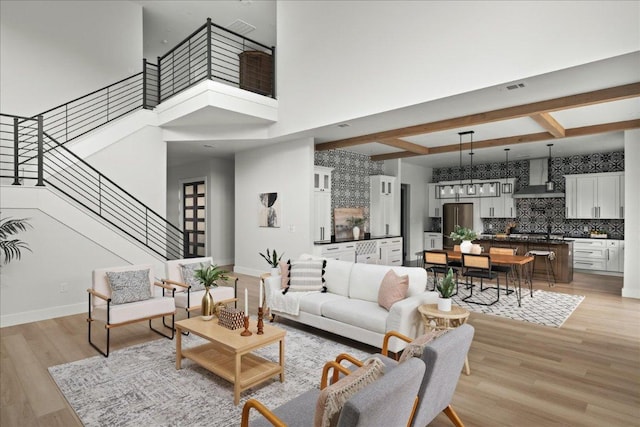 living area with stairway, baseboards, and light wood-style flooring