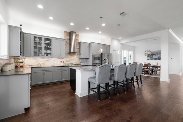 kitchen with visible vents, backsplash, gray cabinetry, wall chimney range hood, and appliances with stainless steel finishes