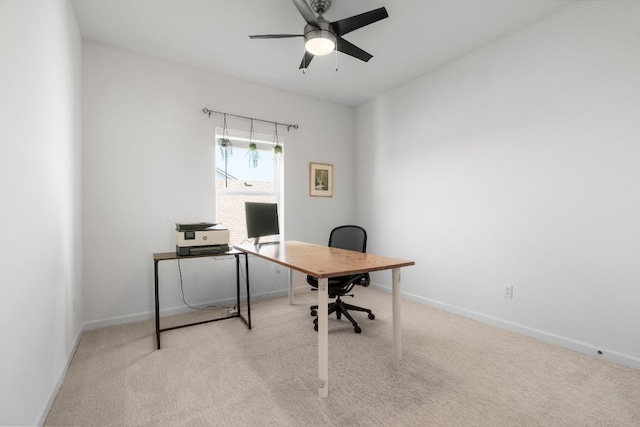 carpeted office space featuring a ceiling fan and baseboards