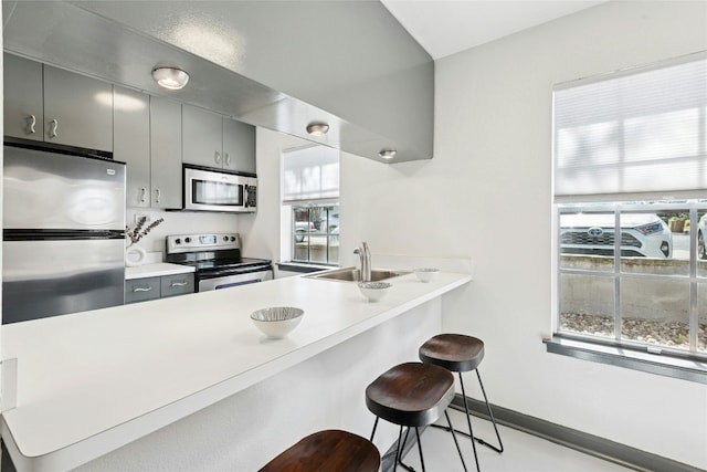 300 Crockett St Unit 118, Austin, TX 78704 - kitchen featuring appliances with stainless steel finishes, a sink, a breakfast bar area, a peninsula, and light countertops