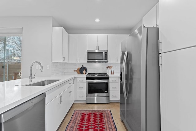 kitchen featuring a sink, decorative backsplash, light countertops, white cabinets, and appliances with stainless steel finishes