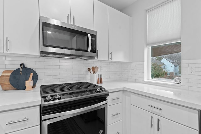 kitchen with decorative backsplash, white cabinets, stainless steel appliances, and light countertops