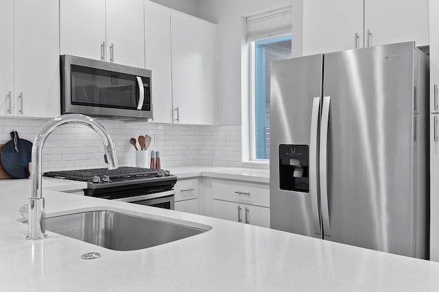 kitchen with decorative backsplash, appliances with stainless steel finishes, white cabinetry, and light countertops