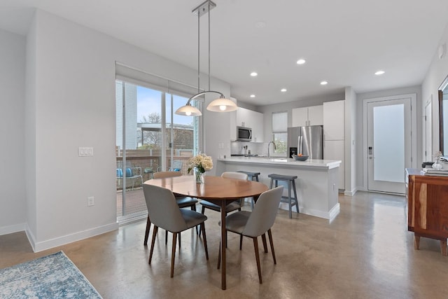 dining space with finished concrete floors, recessed lighting, plenty of natural light, and baseboards