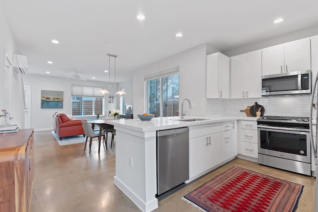 kitchen with open floor plan, an AC wall unit, decorative backsplash, stainless steel appliances, and a sink