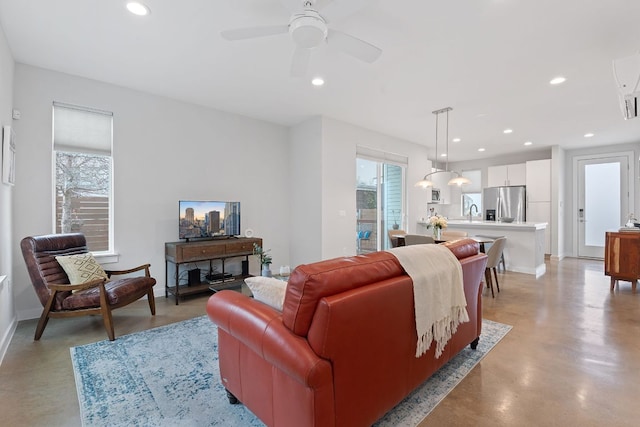 living area featuring a ceiling fan, recessed lighting, finished concrete flooring, and a healthy amount of sunlight