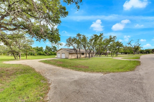 view of front of home featuring dirt driveway, an attached garage, and a front lawn