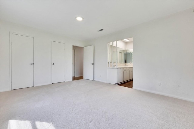 unfurnished bedroom featuring visible vents, baseboards, carpet, and ensuite bathroom