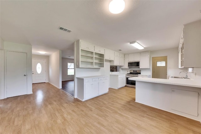 kitchen featuring a peninsula, light wood-style floors, visible vents, and appliances with stainless steel finishes