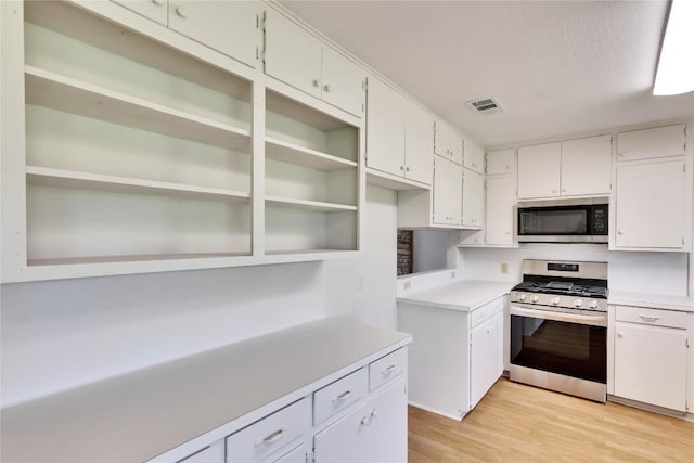 kitchen with visible vents, stainless steel appliances, light countertops, white cabinets, and light wood-type flooring