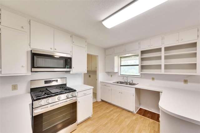 kitchen featuring a sink, open shelves, light countertops, and stainless steel appliances