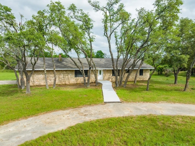 view of front facade featuring a front lawn, stone siding, and driveway