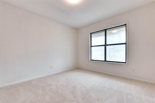 empty room featuring light carpet and baseboards