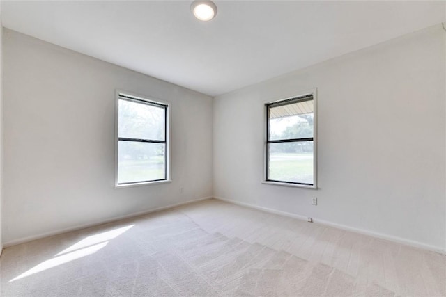 unfurnished room with baseboards and light carpet