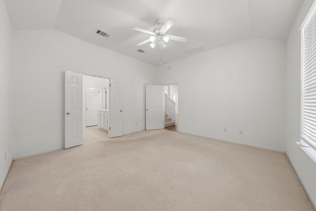 unfurnished bedroom with a ceiling fan, visible vents, ensuite bath, vaulted ceiling, and light carpet