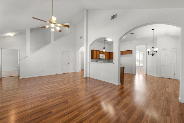 unfurnished living room featuring wood finished floors, visible vents, baseboards, lofted ceiling, and ceiling fan with notable chandelier