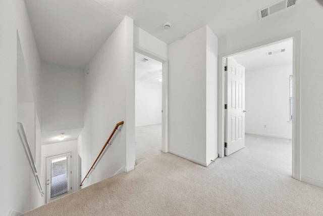 hall with visible vents, an upstairs landing, baseboards, and carpet flooring