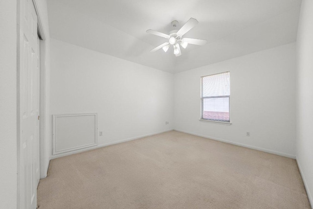 empty room featuring baseboards, light colored carpet, and a ceiling fan