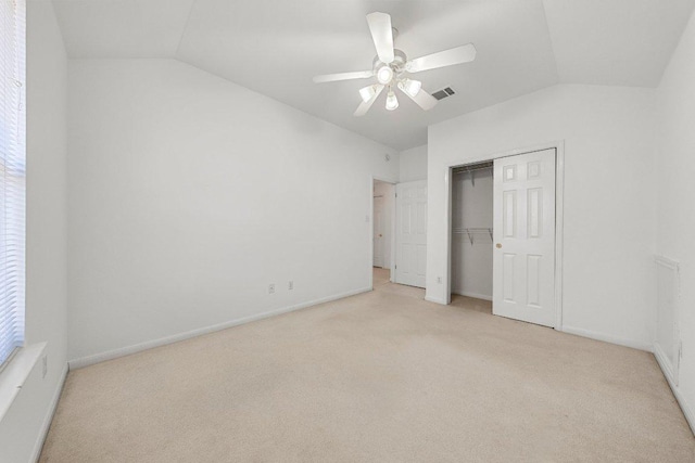 unfurnished bedroom featuring lofted ceiling, visible vents, a closet, and light carpet