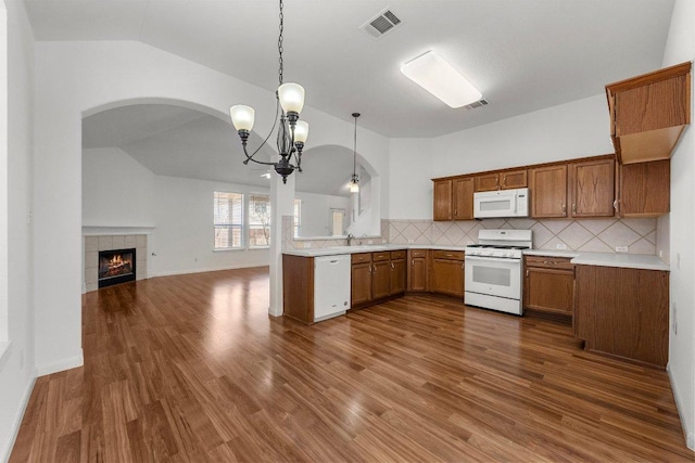 kitchen with dark wood finished floors, brown cabinets, white appliances, and lofted ceiling