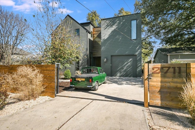 view of front of property featuring a garage, fence, concrete driveway, and a gate