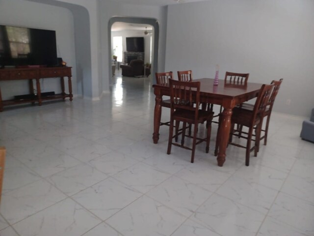 dining area with arched walkways and marble finish floor