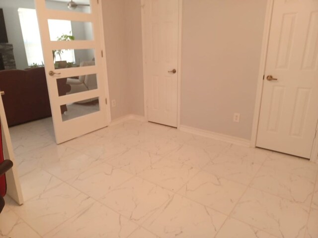 unfurnished room with marble finish floor and baseboards