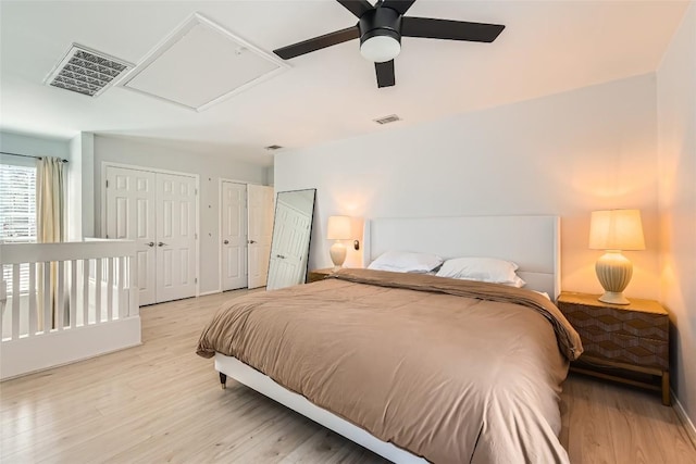 bedroom featuring light wood-type flooring, visible vents, two closets, and a ceiling fan