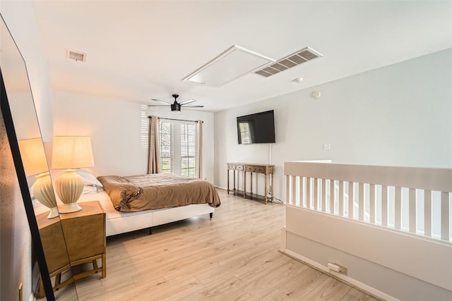 bedroom featuring visible vents, attic access, light wood-type flooring, and ceiling fan