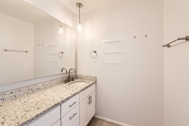 bathroom with vanity, wood finished floors, and baseboards